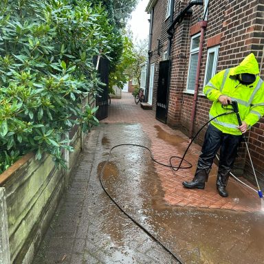 Professional pressure washing a residential pathway with a cleaning machine.