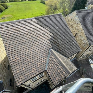 A professional cleaning a residential roof using high equipment.